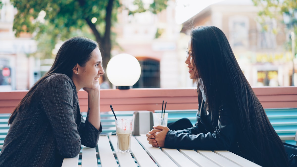 Two friends having a genuine, engaged conversation at an outdoor cafe